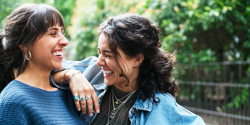 Woman smiling and leaning on her freinds shoulder