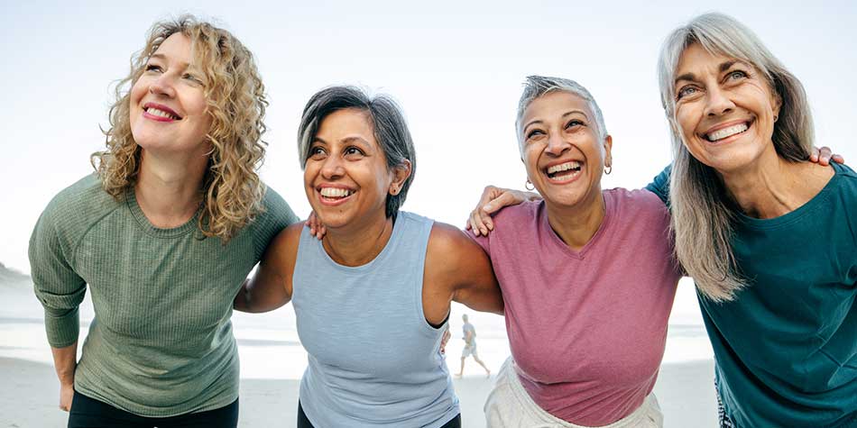 Four women smiling with their arms around each other's shoulders